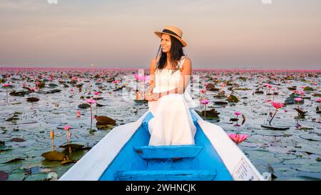Asian women with a hat in a boat at the Red Lotus Sea full of pink flowers in Udon Thani Thailand. Stock Photo