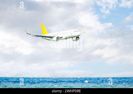 Airplane in the blue sky with clouds flying over the Ocean. close up. flying oder commercial passeng Stock Photo