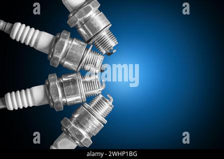 Four spark plugs for a two-stroke engine on a blue gradient background close-up Stock Photo