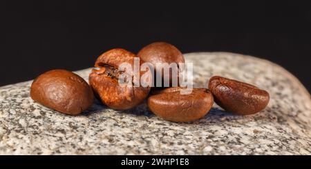 Coffee beans lie on a stone. Macro photography. Stock Photo