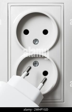 Charger plug on a background of white electrical sockets, close-up Stock Photo