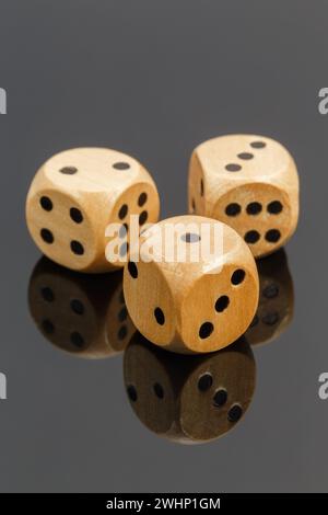 Three wooden dice on a dark background with reflection, close-up Stock Photo