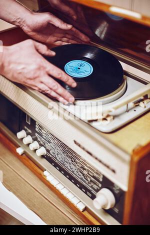 Istra, Russia - September 06, 2021: Vinyl record, spinning on turntable, Vintage record player with radio 60's. Mens hands putti Stock Photo