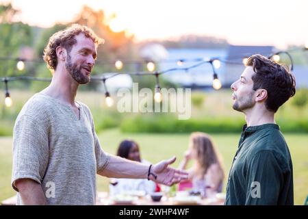Heartfelt Conversations: Friends at Evening Garden Party Stock Photo