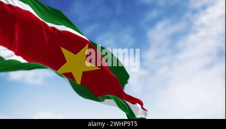 Suriname national flag waving in the wind on a clear day. 5 horizontal bands: green, white, red, white, green, yellow star in th Stock Photo