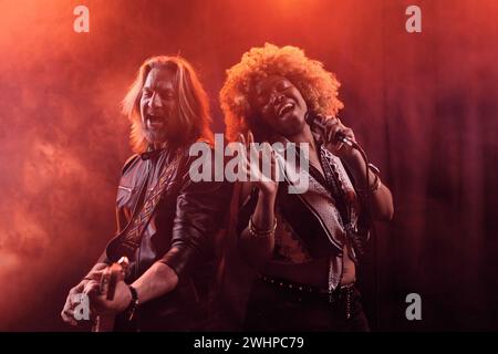 Waist up portrait of soul band performing on stage in nightclub African American woman singing with guitarist Stock Photo