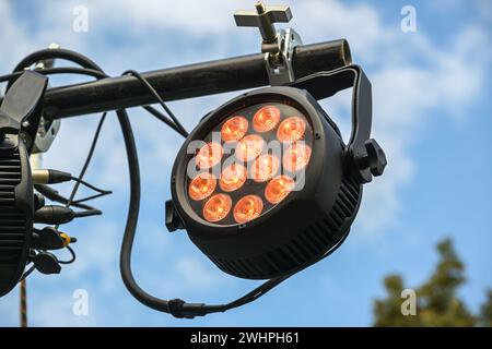LED floodlight with RGB colors as outdoor stage lightning, installed on a black steel beam against the blue sky, used for festiv Stock Photo