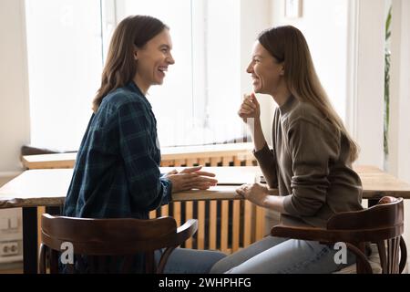 Happy young female business friends talking at workplace table Stock Photo