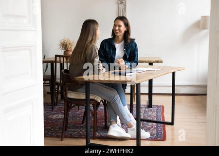 Happy female colleagues discussing work projects in stylish co-working apartment Stock Photo