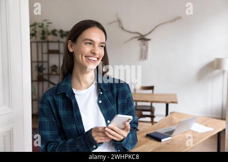 Cheerful young woman using mobile phone in office apartment Stock Photo
