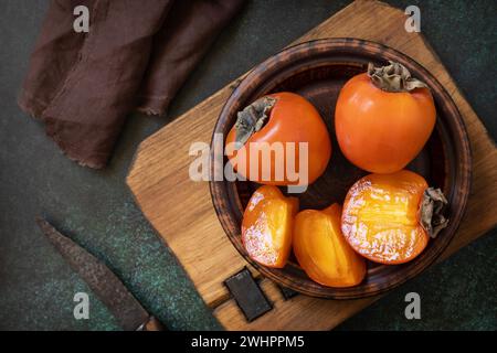 Fresh organic ripe Persimmons fruits in wooden bowl. Stock Photo