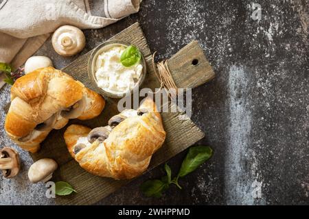 French pastry, tasty freshly baked sandwich. Vegan food style. Croissant with cream cheese and mushroom on a stone background. Stock Photo