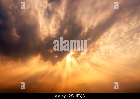 Beautiful dramatic golden sky with sunbeam and light rays through the cloud in the sunset Stock Photo