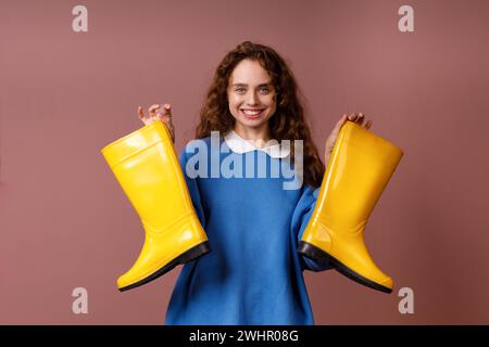 Young positive smiling woman holds in her hands a rubber boots. Stock Photo