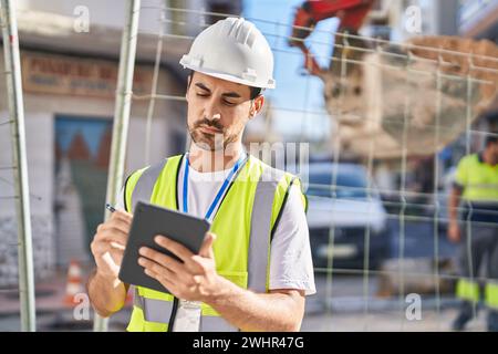 Young hispanic man architect drawing on touchpad at street Stock Photo