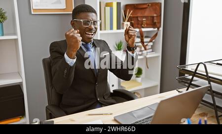 Exuberant black man celebrating success in modern office environment Stock Photo