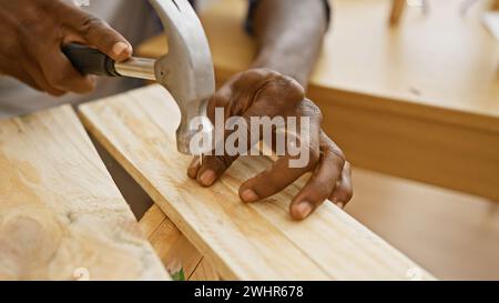 African american man working with hammer in sunny carpentry workshop. Stock Photo