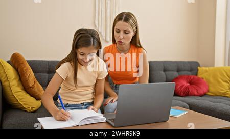 Mother and daughter focused on homework together in a cozy indoor setting. Stock Photo