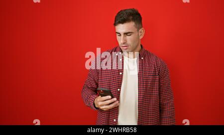 Young hispanic man using smartphone over isolated red background Stock Photo