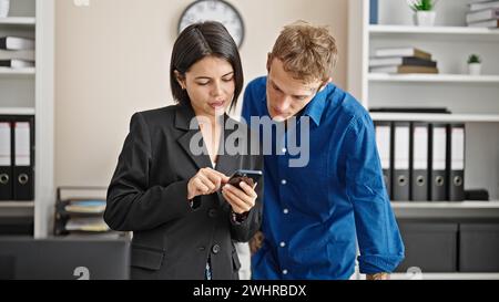 Two business workers using smartphone working at the office Stock Photo