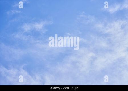 A serene sky scene with fluffy white clouds floating against a bright blue backdrop, epitomizing tranquility and open space. Stock Photo