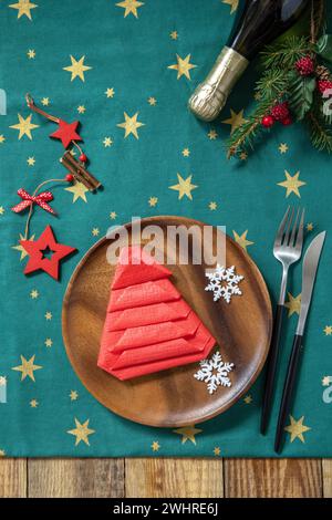 Table setting for Christmas dinner, holiday composition. Table fork and knife set with red paper napkin and fir branch on a rust Stock Photo