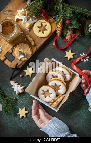 Preparing a homemade sweet present. Linzer Christmas or New Year cookies filled with peanut butter on a dark stone tabletop. Top Stock Photo