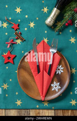 Table setting for Christmas dinner, holiday composition. Table fork and knife set with red paper napkin and fir branch on a rust Stock Photo