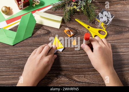 Instruction step 9. Christmas greeting card gift origami candle on wooden table. Childrens art project, handmade, crafts for kid Stock Photo