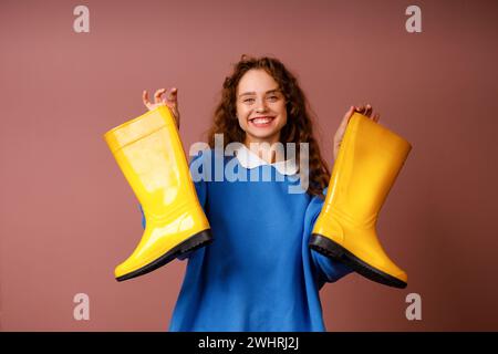 Young positive smiling woman holds in her hands a rubber boots. Stock Photo