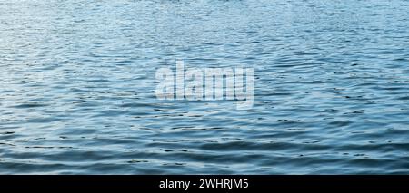 Rippled empty sea background texture. Wavy with reflection light blue ocean water surface. Marine vacation ad template, copy space. Stock Photo