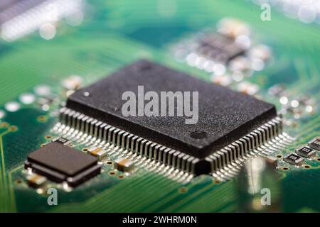 macro shot of a black computer chip on a green circuit board Stock Photo