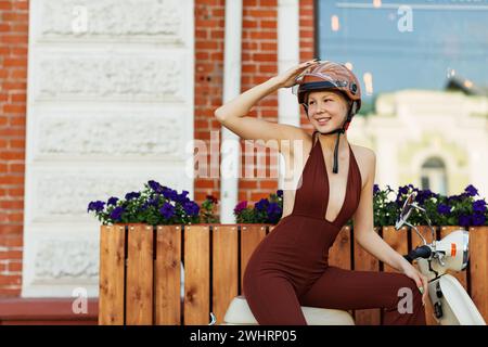 Young woman riding on motorbike moped scooter in city street. Stock Photo