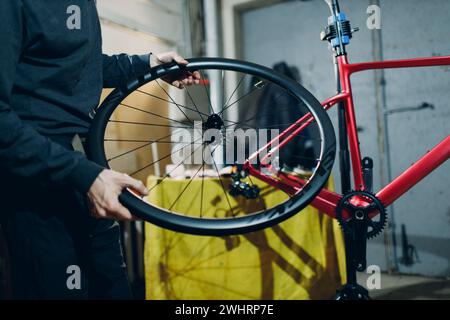 Mechanic repairman assembling wheel custom bicycle in workshop. Stock Photo