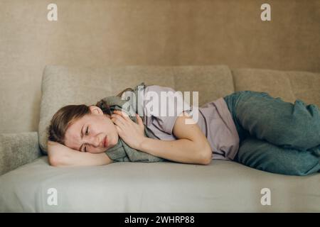 Young woman wearing scarf has flu ill sick disease cold at home indoor. Stock Photo