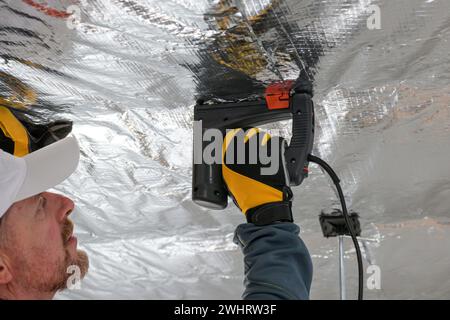 the construction worker holds a vapor barrier in his hand - preparation ...