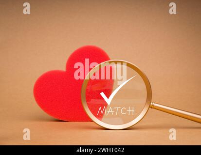 Love match, couple lover, matching partners meeting online concept. Match, words with checkmark icon in gold magnifying glass, looking on big red hear Stock Photo