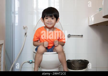 Asian boy Sitting on the toilet bowl Stock Photo