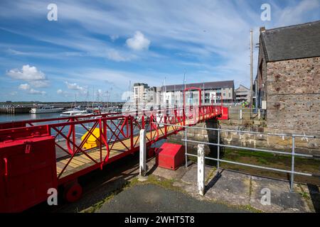 Red footbridge beside the Victoria Dock area of Caernarfon on the coast of North Wales. Stock Photo