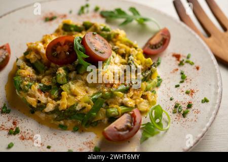 Scrambled eggs with green asparagus and cherry tomatoes. Stock Photo