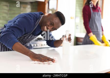Happy diverse couple cleaning countertop and doing dishes in kitchen at home Stock Photo