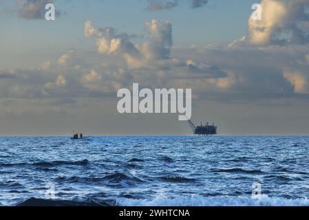 boat sailing to the gas platform against the sky at sunset in Israel Stock Photo