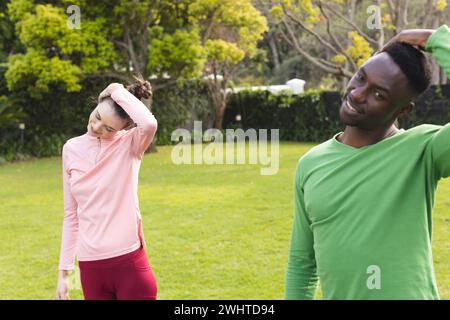 Happy diverse couple practicing yoga and stretching in garden Stock Photo