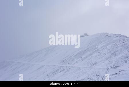 Tourists approaching the top of Mount Sniezka in very difficult weather conditions. Changing weather conditions in the mountains and icy trails cause Stock Photo