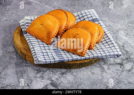 Three delicious pumpkin pies placed on a rustic wooden bowl, adorning a crisp white and blue cloth Stock Photo