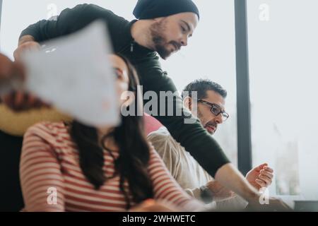 Photo of a cross generational creative team intensely discussing projects in a bright office setting, displaying teamwork and collaboration. Stock Photo