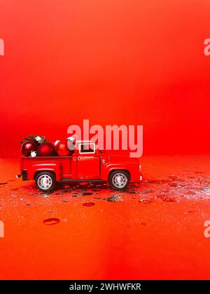 Red toy truck with Christmas balls and fir branch in its trunk. Stock Photo