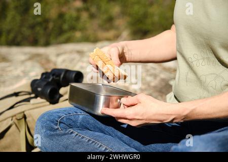 Woman seated taking out a sandwich out of a stainless steel lunch box Stock Photo