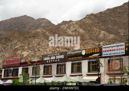 Signs written in Chinese carachters, Tibetan script and English mark a shops in a strip mall in Lhasa area of Tibet Autonomous Region of China. Stock Photo