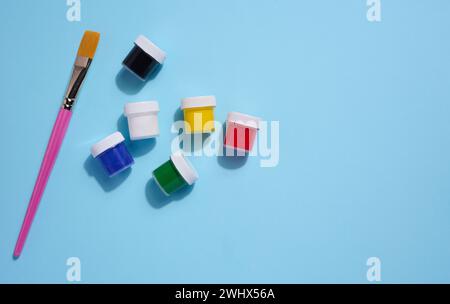Plastic jars with multi-colored gouache on a blue background, copy space Stock Photo